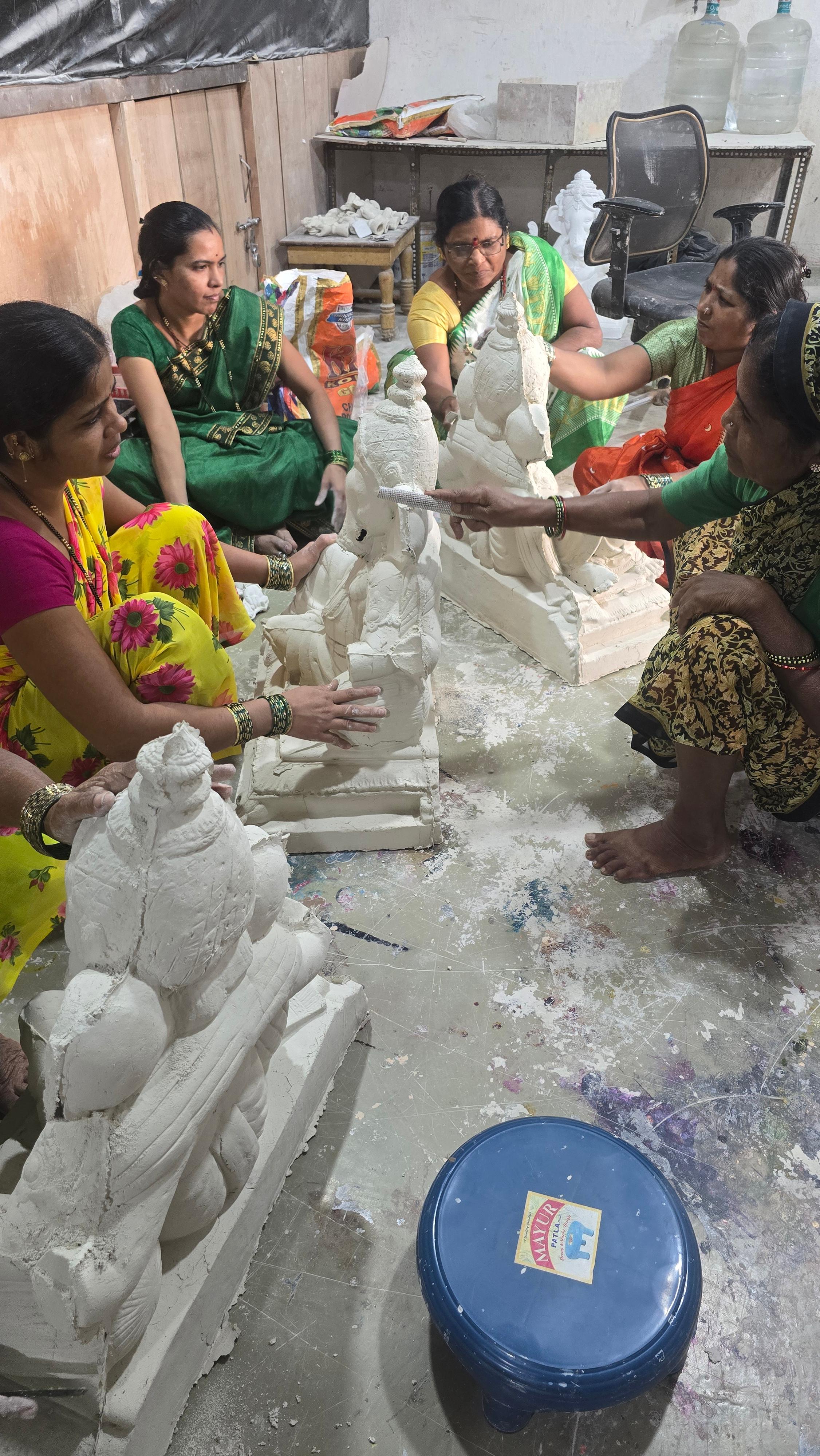 Women artisans working together on clay Ganesha idols