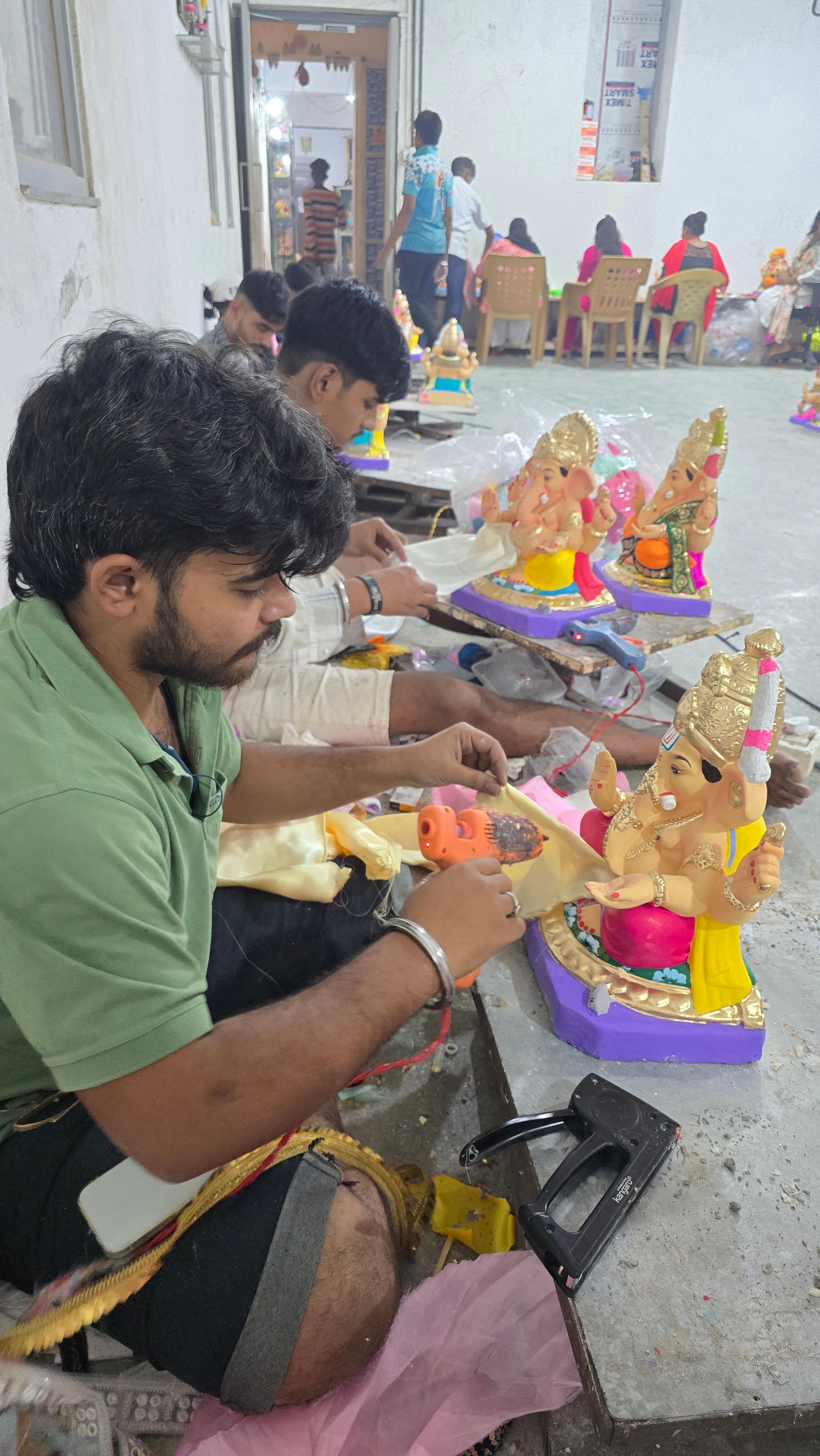 Artisans painting intricate details on Ganesha idols